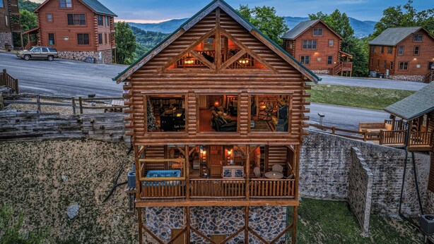Eine Blockhütte mit Balkon, Steinmauer und Blick auf die Umgebung.
