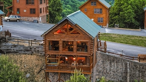 Eine Blockhütte mit Balkon, einer Steinmauer und einer Straße im Hintergrund.