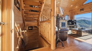 Ein Holzinnenraum mit Treppe, Kamin, Fernseher und Blick ins Freie.