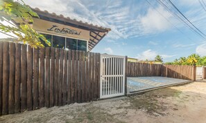 A wooden fence with a gate, a sign reading "Imbassaí Top Flats", and a paved area with a wheelchair symbol. - Condominium w/ Pool, 900 m fr/ the Beach, Imbassai Top Flats - Itfs (Mata de São João)