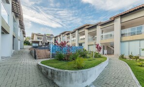 A modern building with multiple balconies, a paved walkway, and a landscaped garden area. - Condominium w/ Pool, 900 m fr/ the Beach, Imbassai Top Flats - Itfs (Mata de São João)