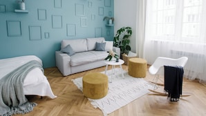 Een moderne woonkamer met een lichtblauwe wand, een grijze bank, een witte salontafel en een witte stoel.