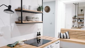 Een moderne keuken met houten planken, een zwart aanrecht en een bank met gekleurde kussens.