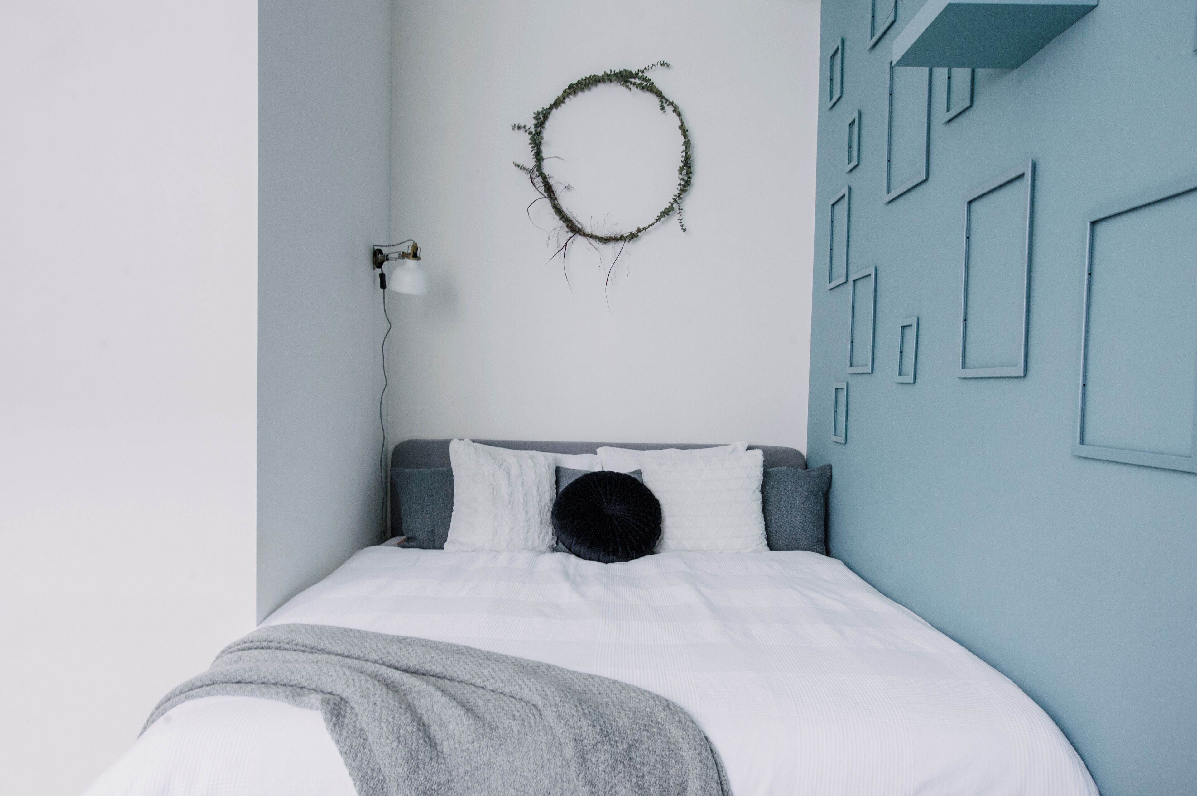 A bedroom with a bed, a wall-mounted light, and a geometric wall design.