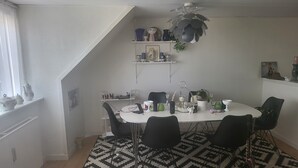 Et spiseområde med et hvidt bord, sorte stole, et gulv med mønster og en loftsvifte.
