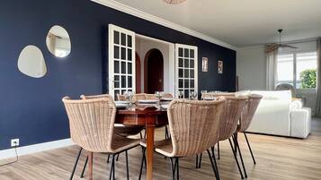 Un coin repas avec un mur bleu foncé, une fenêtre à cadre blanc et un ventilateur de plafond.