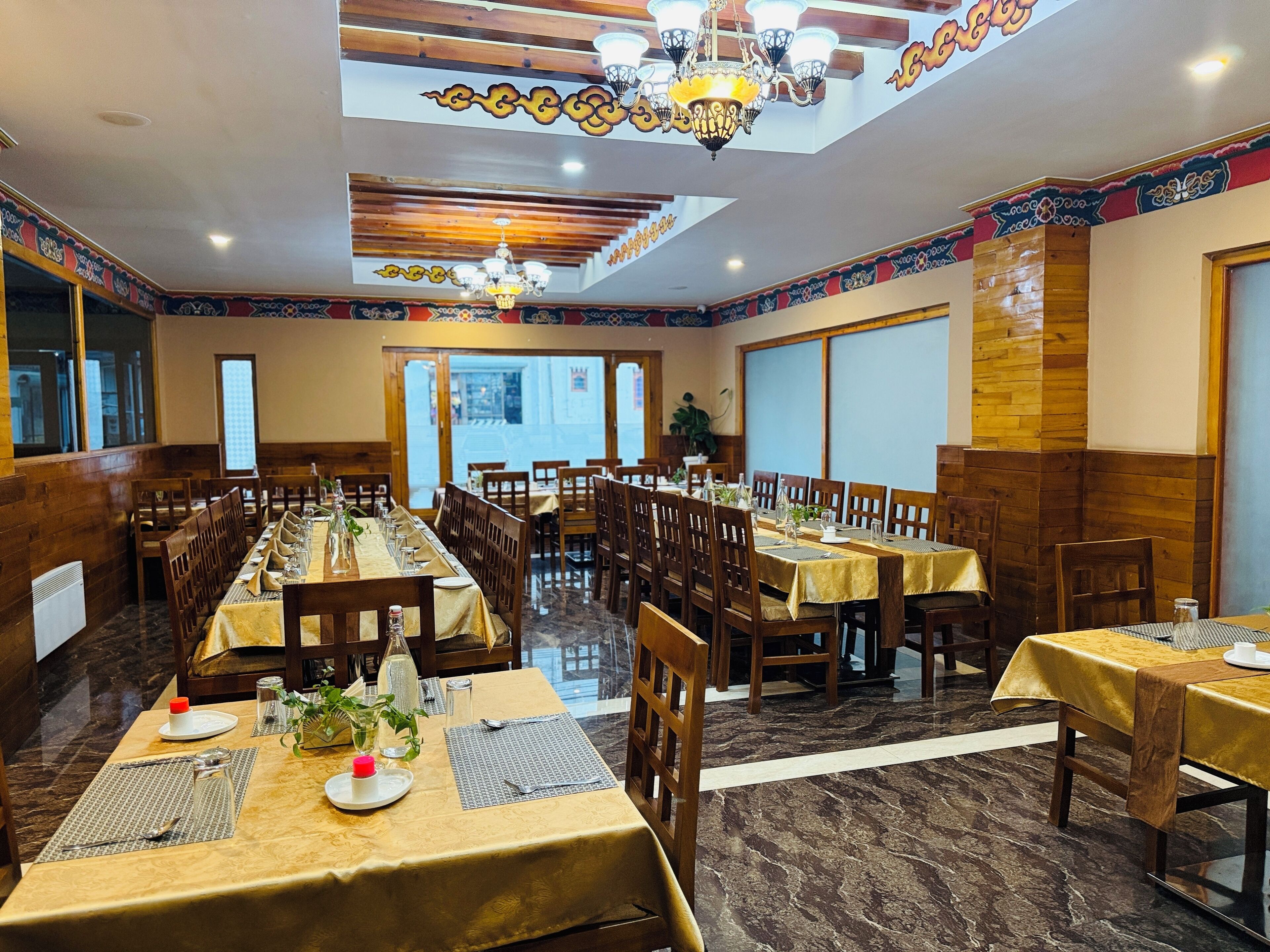 A restaurant with multiple tables set for dining, wooden paneling, and a chandelier.