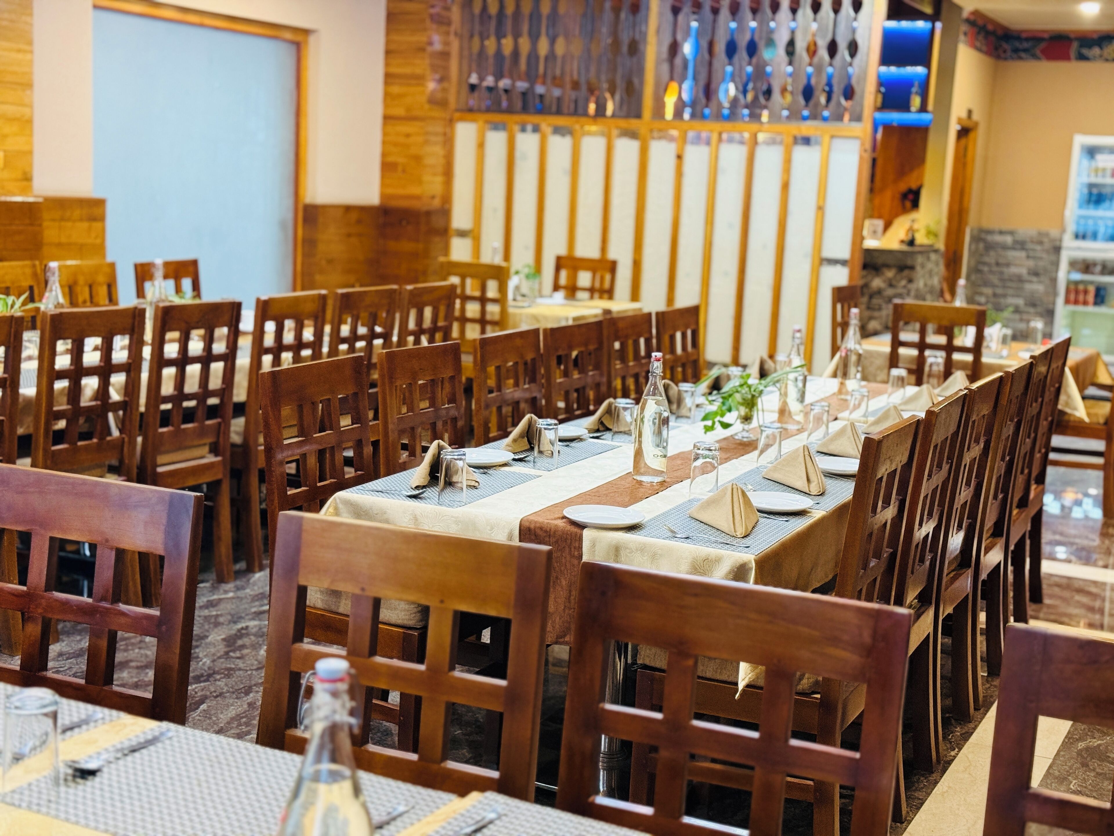 A restaurant with wooden chairs and tables set for dining.