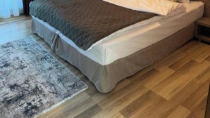 Une chambre à coucher moderne avec un grand lit, une table de chevet, une commode, un radiateur et une fenêtre avec des rideaux.