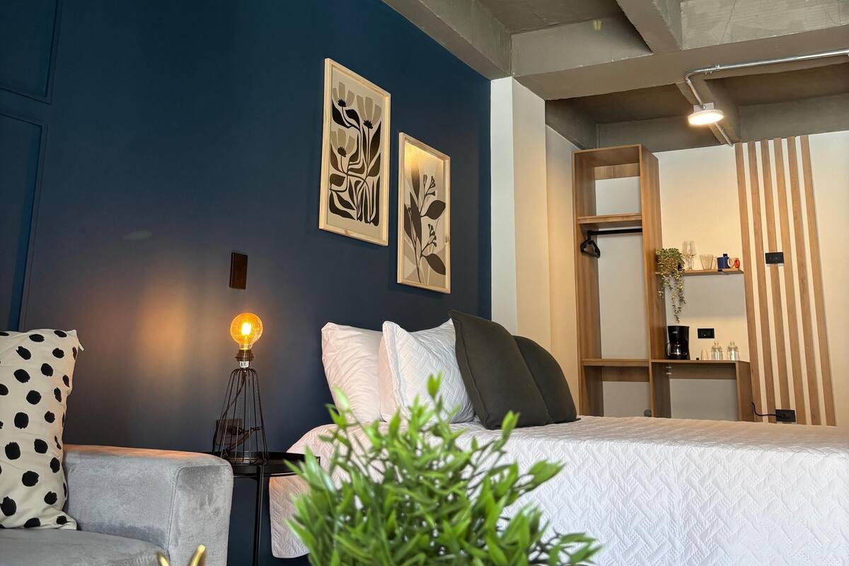A bedroom with a bed, a nightstand, a lamp, and two wall-mounted pictures.