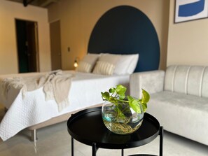 Un dormitorio con una cama, una mesita de noche con una planta, un sofá y una pared con un arco azul grande.