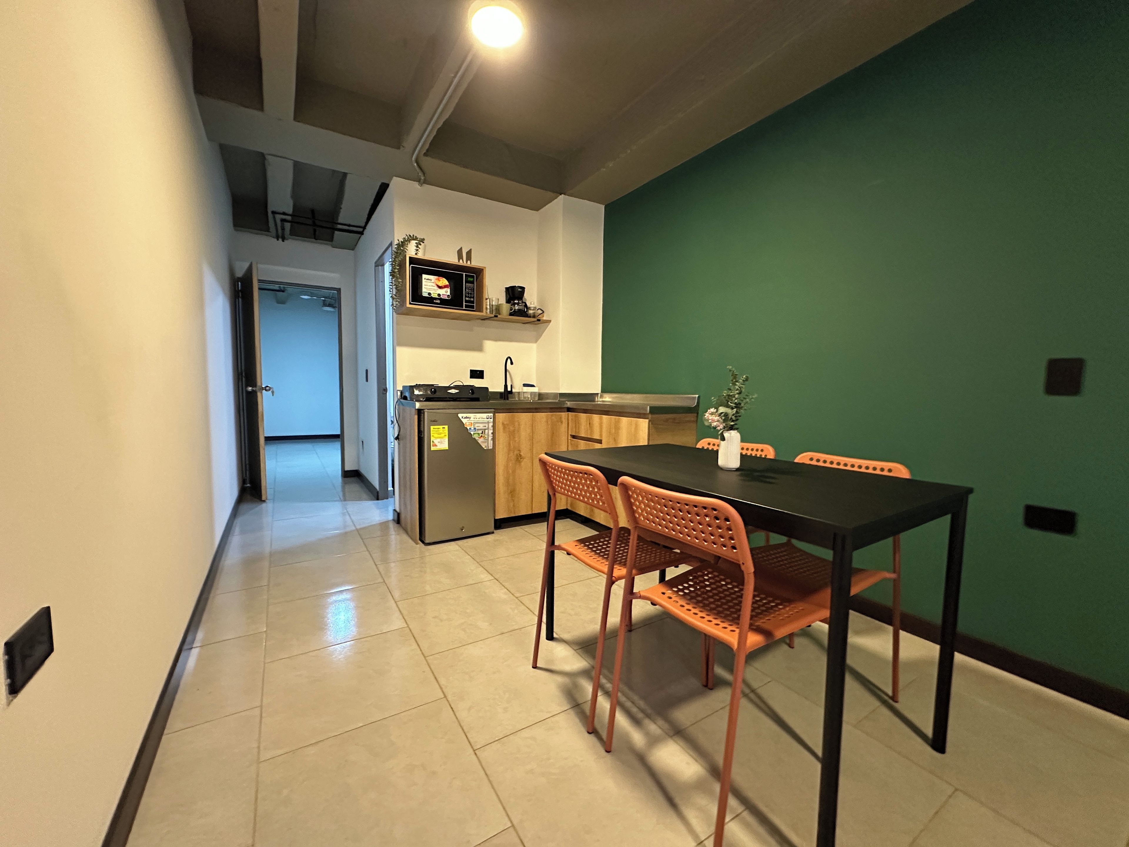 Een eetruimte met een tafel, stoelen en een keuken op de achtergrond.