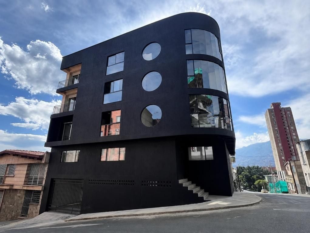 Een modern gebouw met een gebogen gevel, meerdere balkons en een trap naar een hoger gelegen niveau.