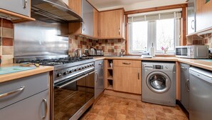 Una cocina moderna con electrodomésticos de acero inoxidable, armarios de madera y un amplio ventanal.