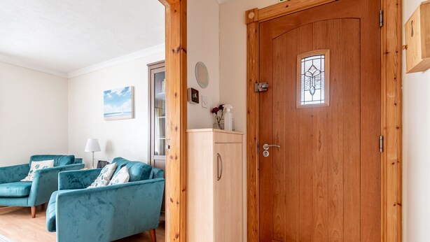 Una sala de estar con dos sofás color turquesa, un aparador de madera y una puerta de madera con un ventanal.
