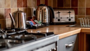 Una cocina con estufa, tetera, tostadora y un cajón.