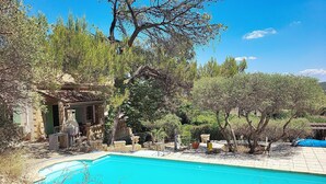 A pool surrounded by stone structures and greenery, with a clear blue sky above. - House with pool in the hills above Aramon (Aramon)