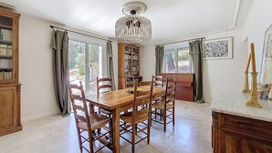 A dining area with a wooden table and chairs, a chandelier, and a bookshelf. - House with pool in the hills above Aramon (Aramon)