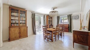 A spacious dining area with a wooden table and chairs, surrounded by bookshelves and a large window with curtains. - House with pool in the hills above Aramon (Aramon)