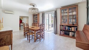 A spacious living room with a wooden dining table, chairs, a bookshelf, and a chandelier. - House with pool in the hills above Aramon (Aramon)