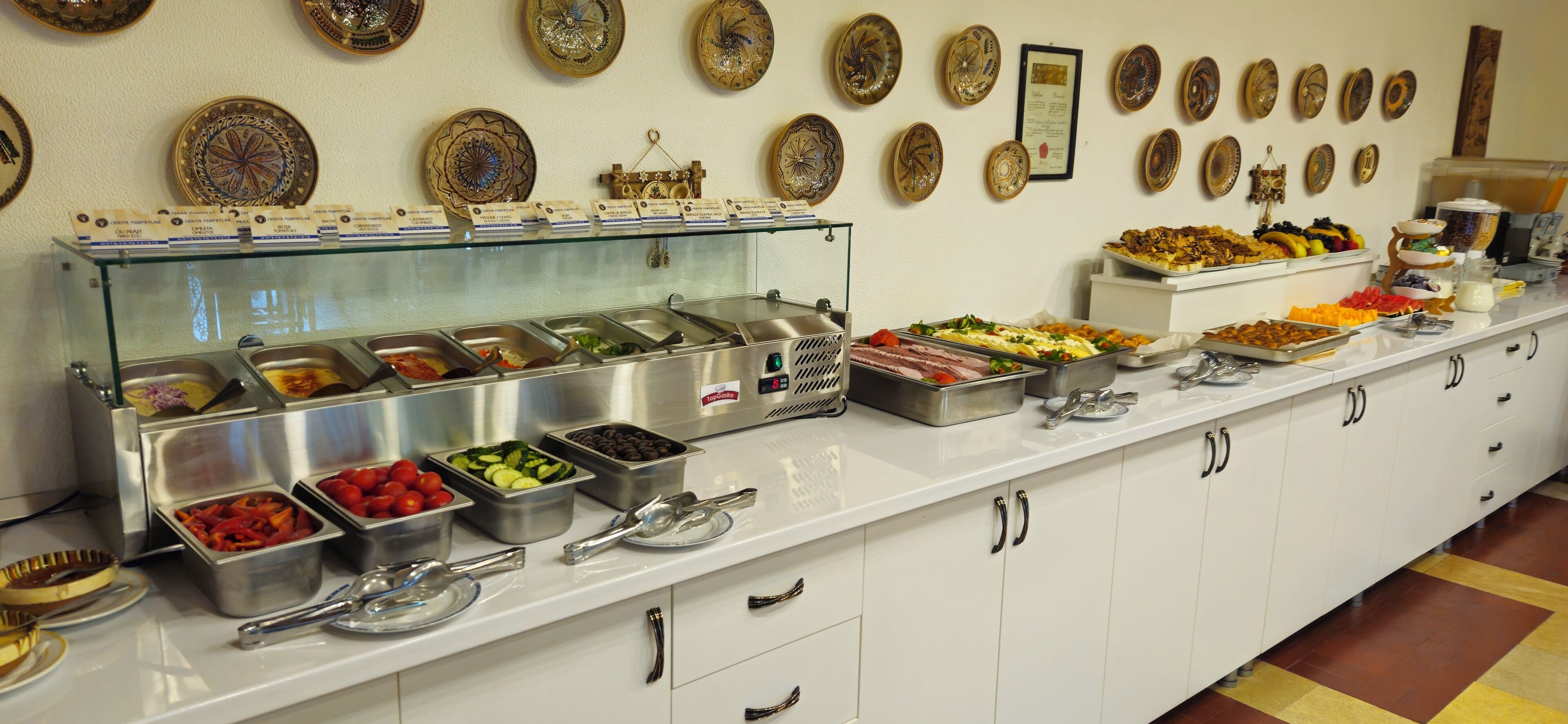 Een buffet met diverse gerechten en een collectie decoratieve borden aan de muur.