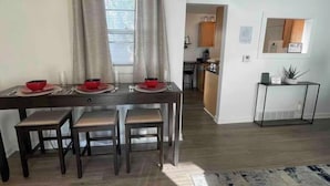 A dining area with a table set for four, a kitchen in the background, and a Wi-Fi sign on the wall. - Cozy Bungalow Retreat (Des Moines)
