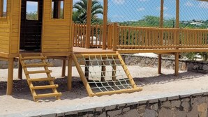 Una estructura de juego de madera con un tobogán y una escalera de cuerda.