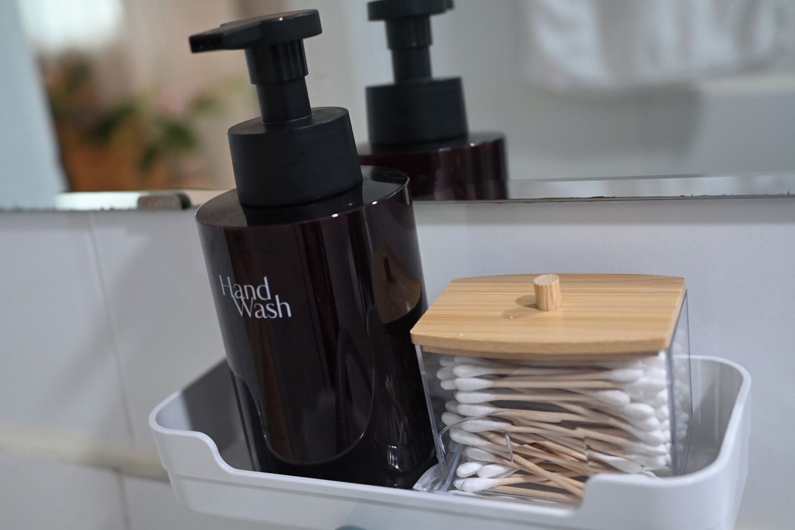 Un lavabo de salle de bain avec un distributeur de savon liquide et un récipient contenant des cotons-tiges.