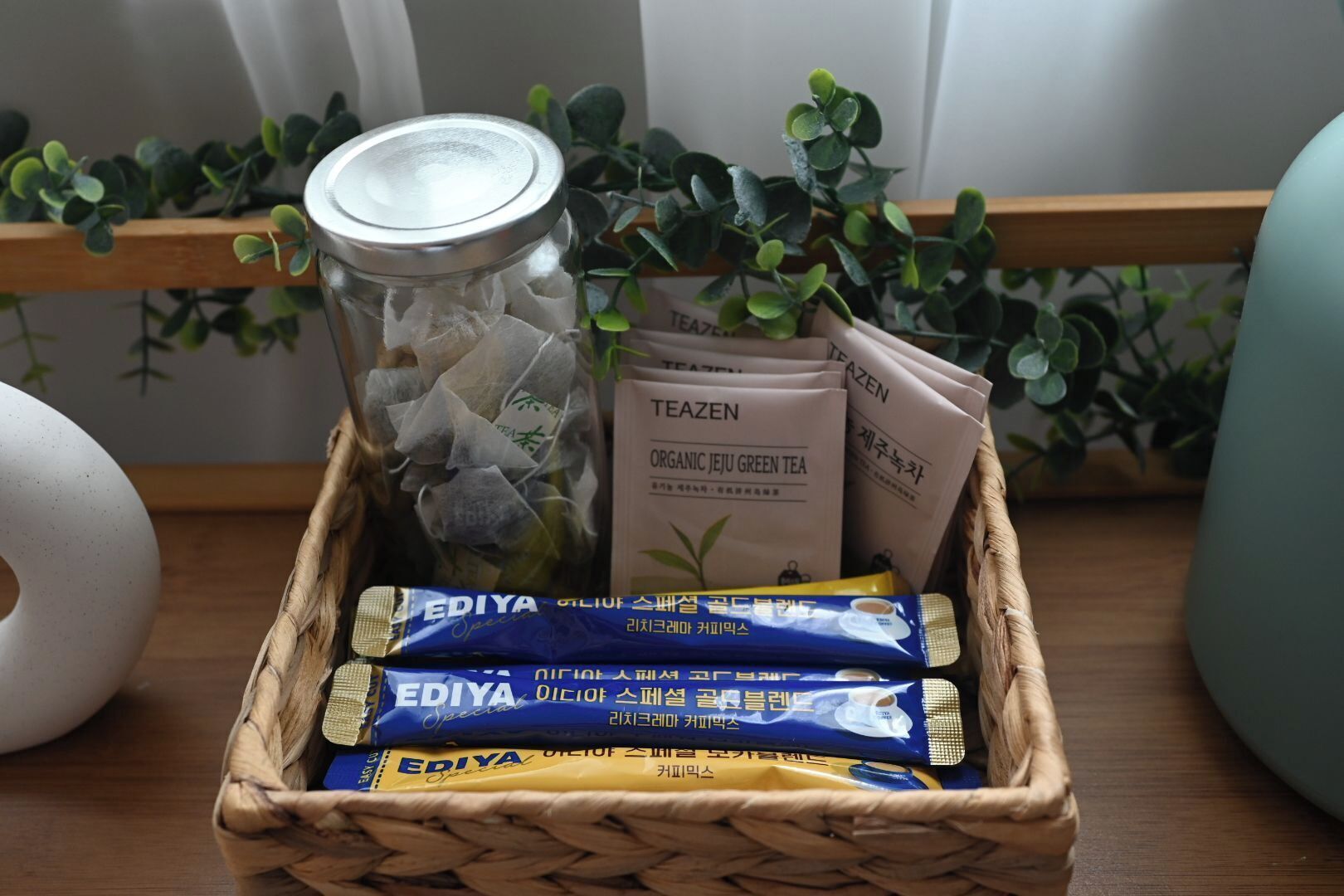A wicker basket containing tea bags, a jar of loose tea, and a tea infuser.