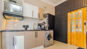 Una cocina compacta equipada con lavadora, cafetera y microondas.