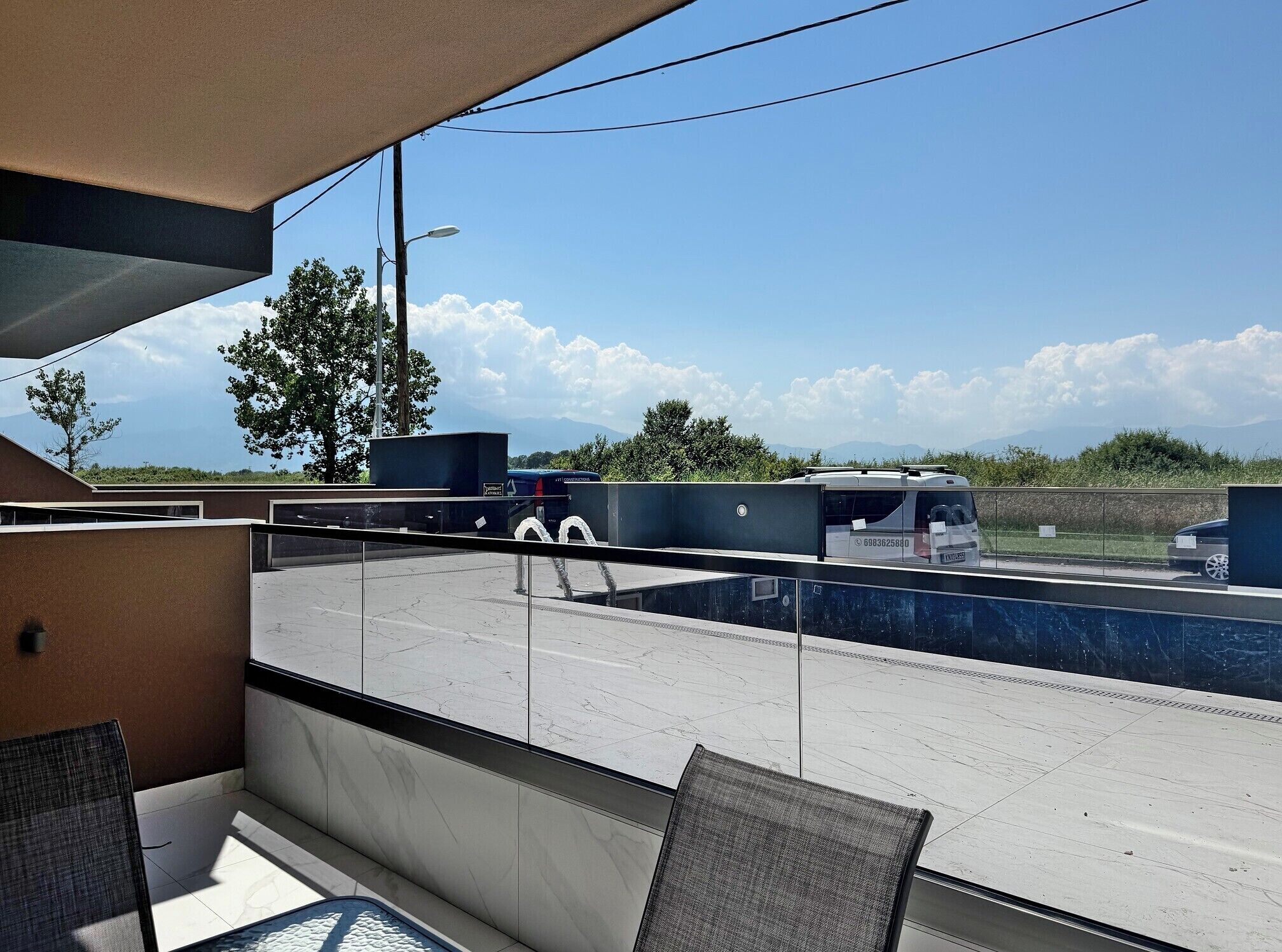 A modern hotel room with a large window overlooking a parking area and a scenic view of trees and mountains.