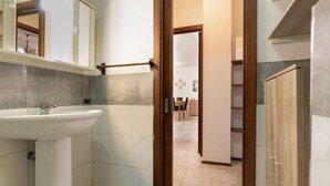 Ein Badezimmer mit Waschbecken, Spiegel und einer Holztür, die in einen Essbereich führt.