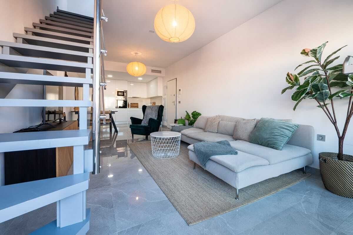 Un salon moderne avec un escalier, un canapé, une table basse et une plante en pot.