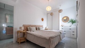 Een moderne slaapkamer met een groot bed, nachtkastjes, een spiegel en een dressoir.