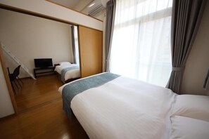 Habitación de hotel con dos camas, un televisor y un armario corredero.