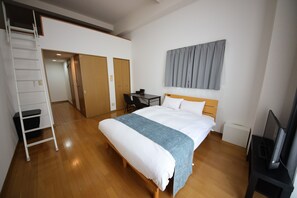 Habitación de hotel con cama, escritorio, silla, televisión, armario y espejo.