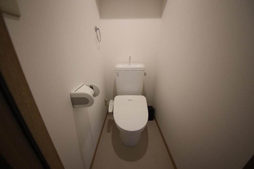 Ein kleines, kompaktes Badezimmer mit Toilette, Toilettenpapierhalter und Duschkopf.