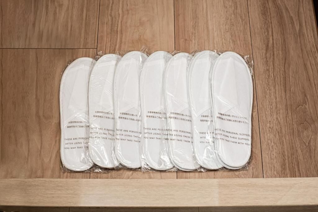 A set of white slippers with text on them, placed on a wooden surface.