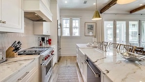 A modern kitchen with white cabinetry, a large island, stainless steel appliances, and pendant lighting. - Grace at Patience 12-Family Escape-Sleeps 10 (Inlet Beach)