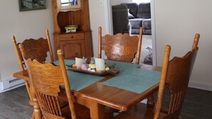 A dining area with a wooden table and chairs, a cabinet, and a painting on the wall. - Rural Cabin along Swift Run River, ten minutes from Shenandoah National Park. (Stanardsville)