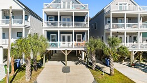 A beachfront multi-story building with balconies, a covered walkway, and palm trees. - Walk to Beach 7BR Home w/ Private Pool & Beachside Charm (Surfside Beach)