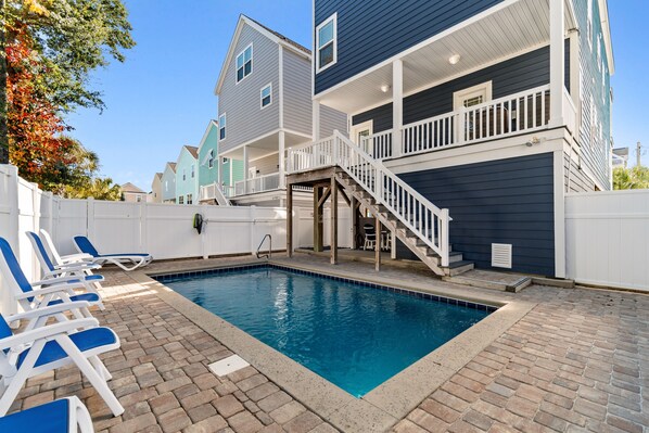 A swimming pool with lounge chairs, a wooden deck, and a staircase leading to a balcony. - Walk to Beach 7BR Home w/ Private Pool & Beachside Charm (Surfside Beach)