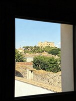 Vista de un castillo histórico en una colina, con edificios y vegetación circundante.