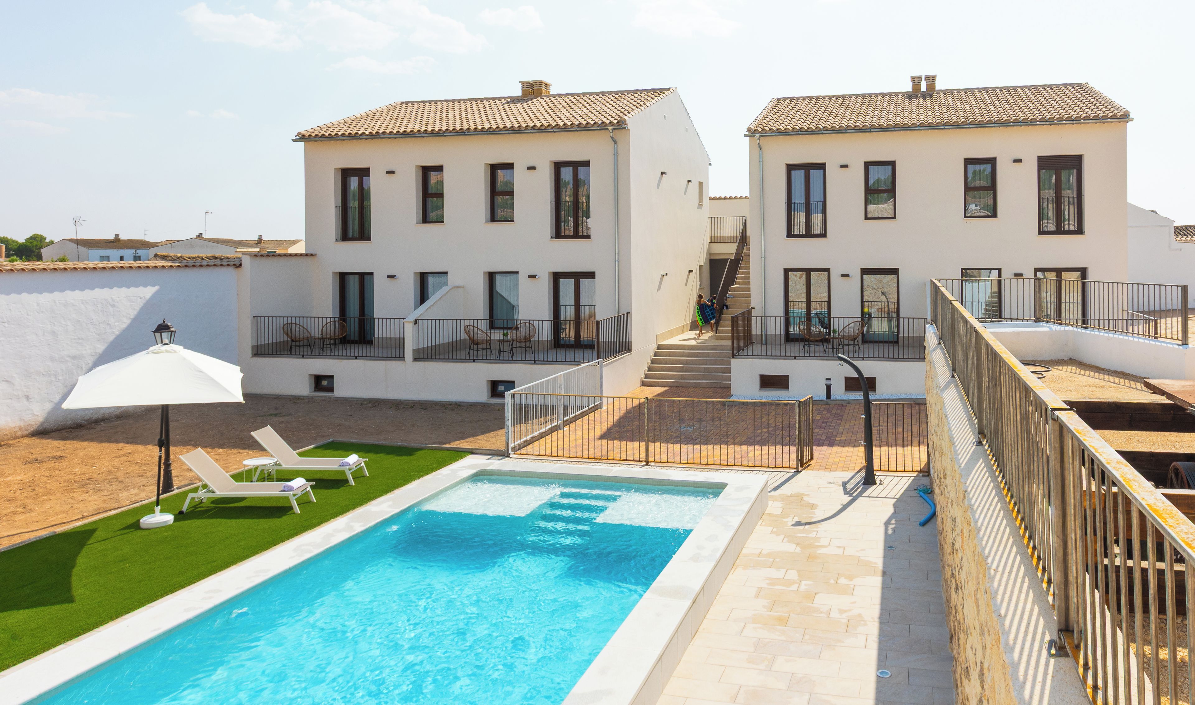 A two-story building with a swimming pool, outdoor seating, and a staircase leading to the upper floor.