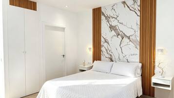 Un dormitorio con cama, mesita de noche, luz empotrada en la pared y una puerta.