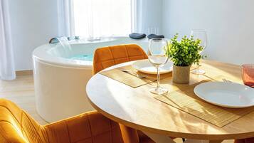 A dining area with a round table, chairs, a hot tub, and a potted plant.