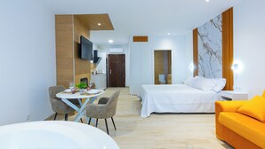 A modern hotel room with a bed, a sofa, a dining area with a table and chairs, a TV, and a bathroom with a bathtub. - Complejo La Serrería (Belmonte)