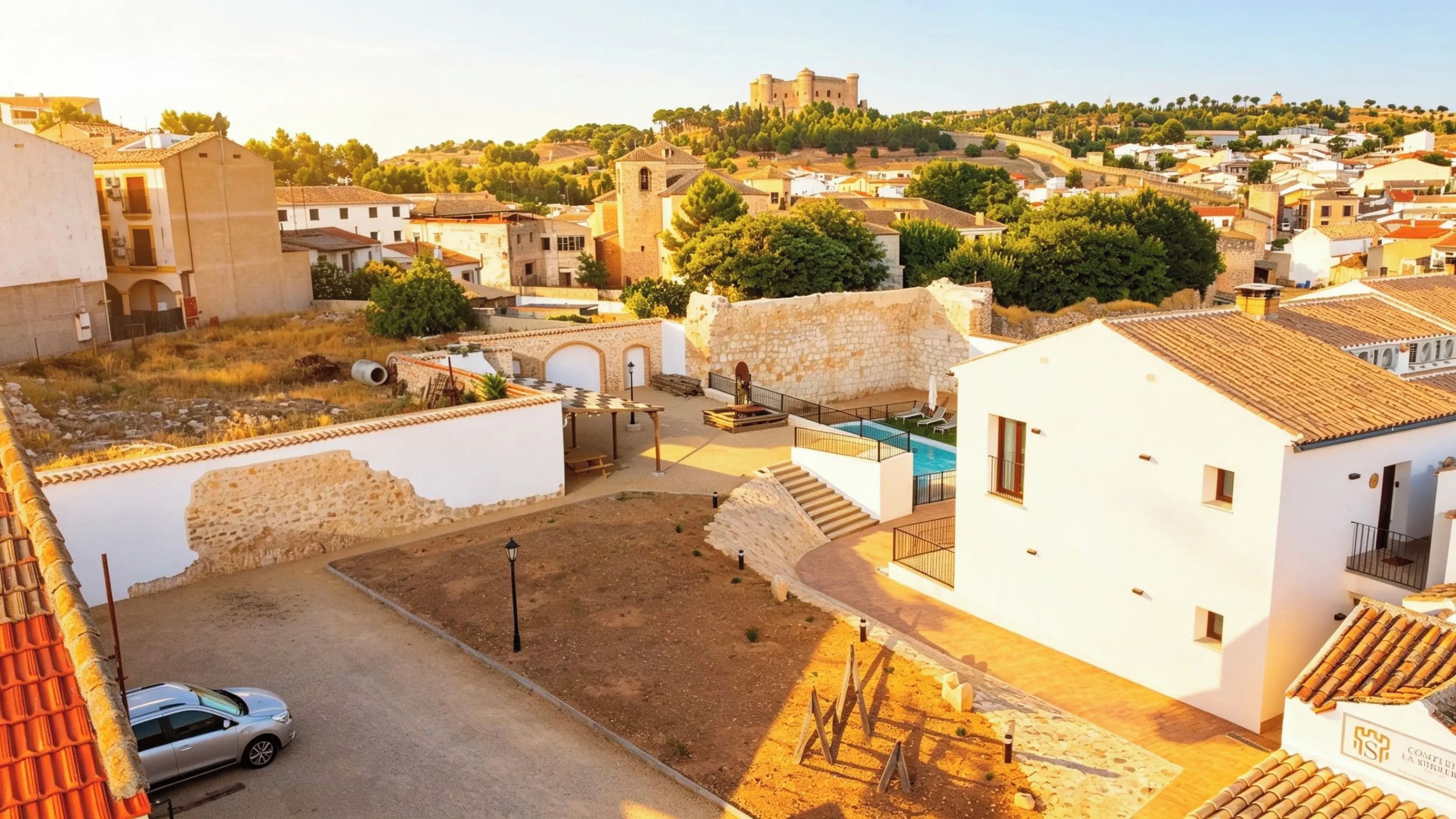Zona residencial con piscina, un coche y un castillo al fondo.