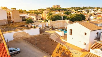 Zona residencial con piscina, un coche y un castillo al fondo.