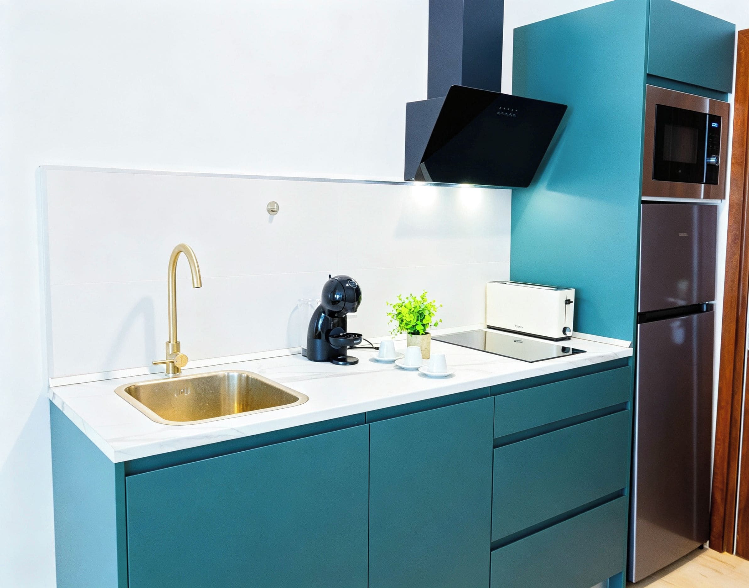 Una cocina moderna con un lavamanos de acero inoxidable, una cafetera, un tostador y un microondas integrado.